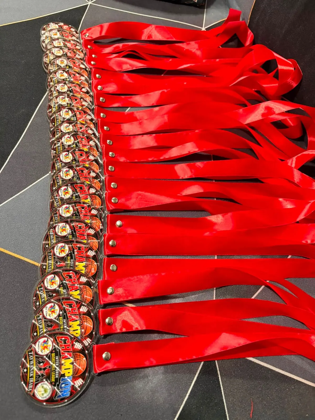 A long row of acrylic basketball medals with red ribbons