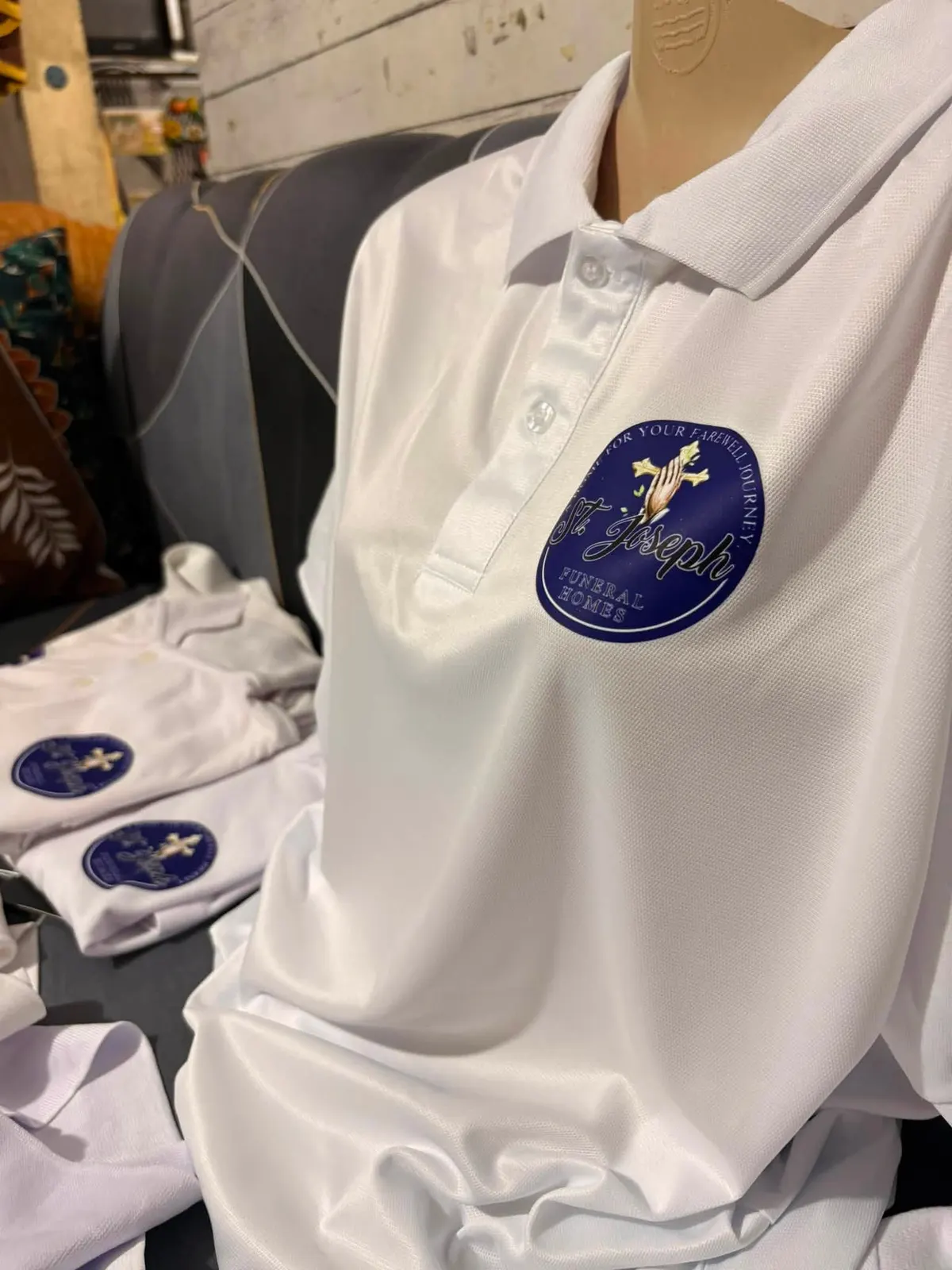White polo on a form, with a circular St. Joseph Funeral Homes mark