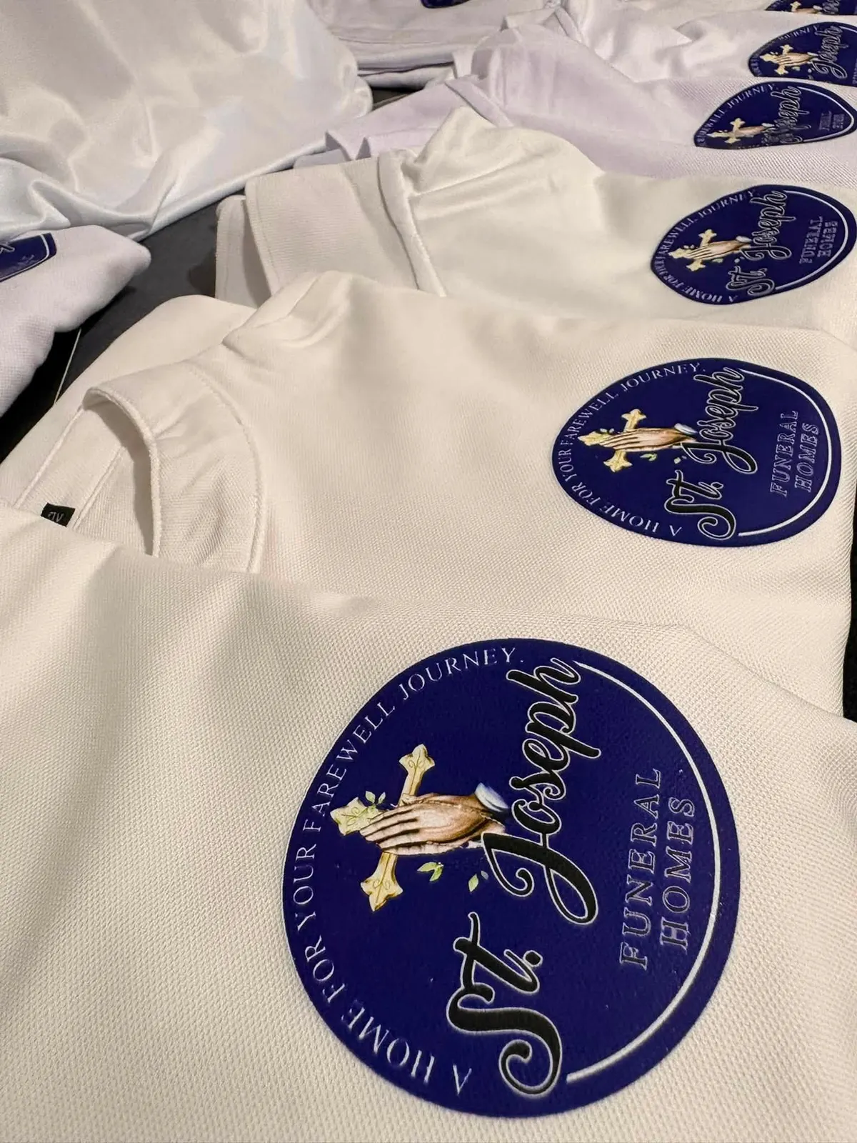 Folded white polos, each with the same circular blue mark